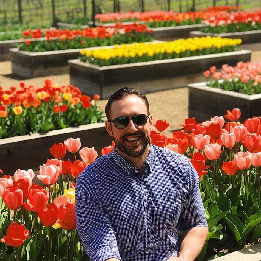 Man in front of flowers wearing castles sunglasses