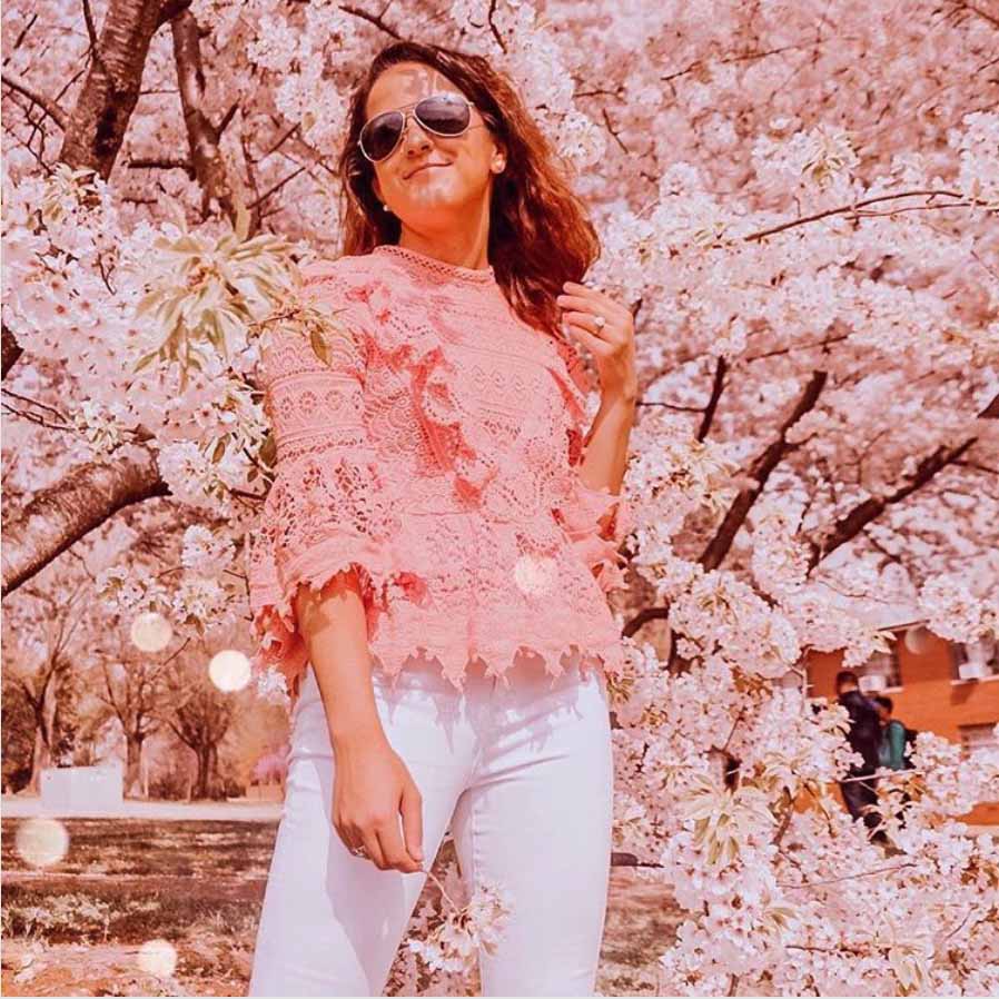Woman in front of pink flowers wearing Mavericks Sunglasses