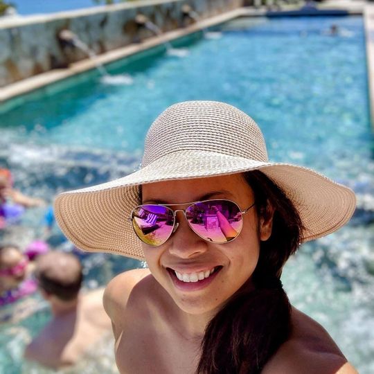 Woman in hat wearing Mavericks sunglasses near pool