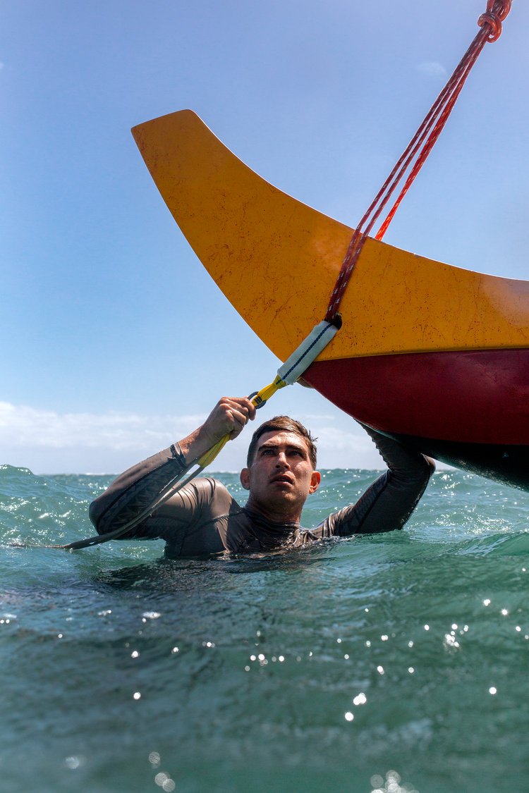 Man in water working on sailing canoe
