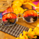 Polarized fashion sunglasses with HAWAII LAVA™ red lenses, resting on a guitar