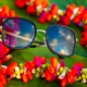 Pua Sunglasses on a leaf surrounded by a colorful lei