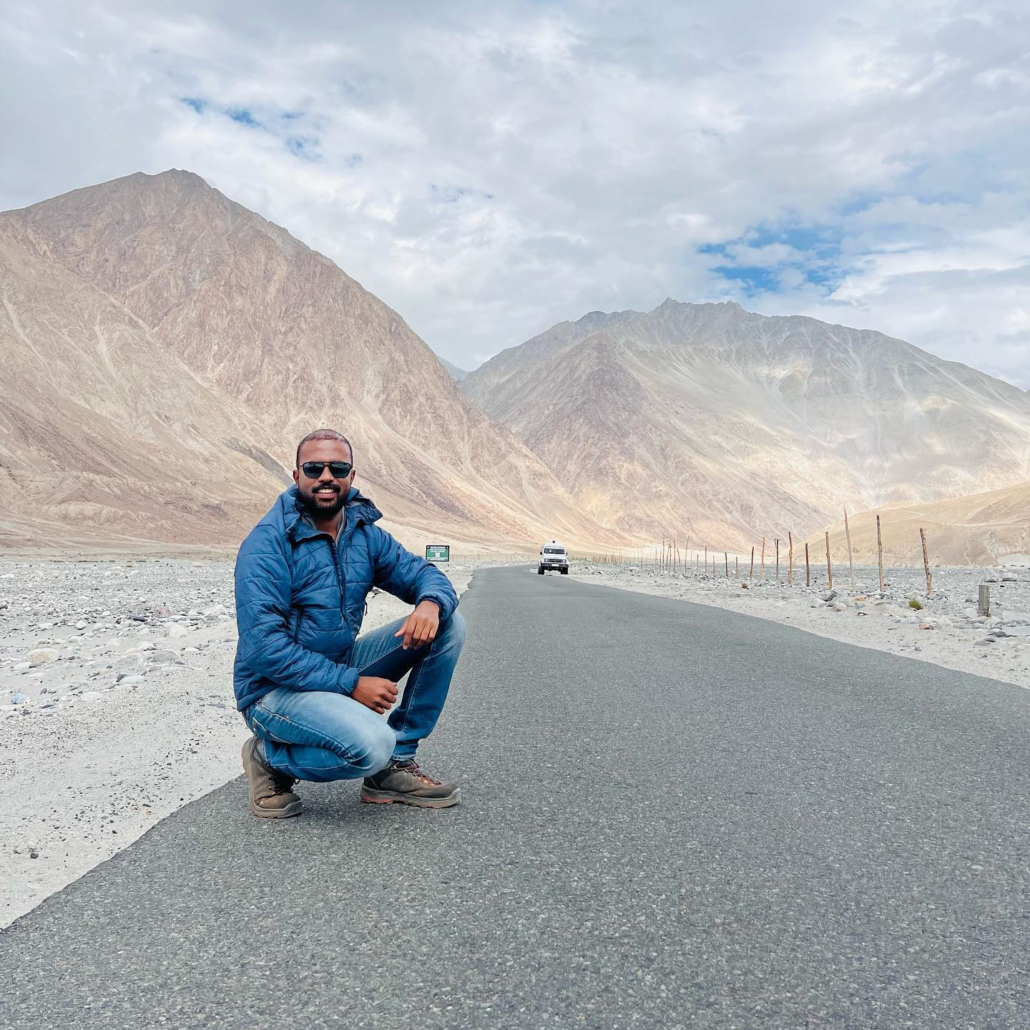 Man in black sunglasses poses in front of a mountain range