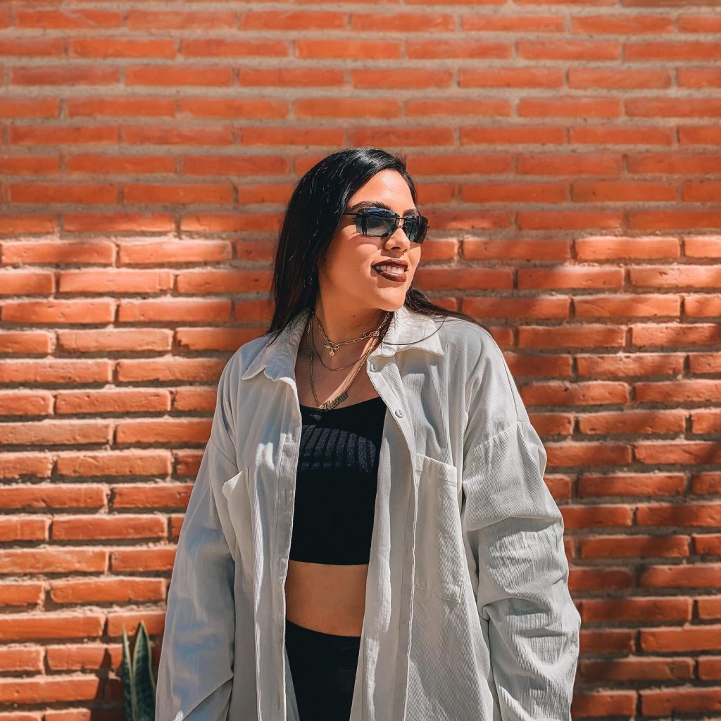 A woman standing next to a brick wall