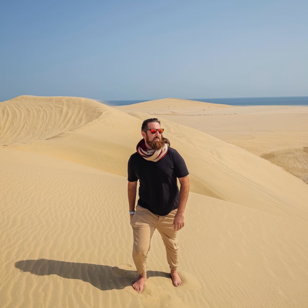 Man in black sunglasses with red lenses poses in the desert