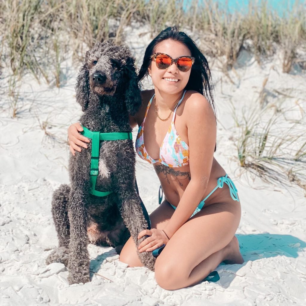A woman on a beach posing with her dog