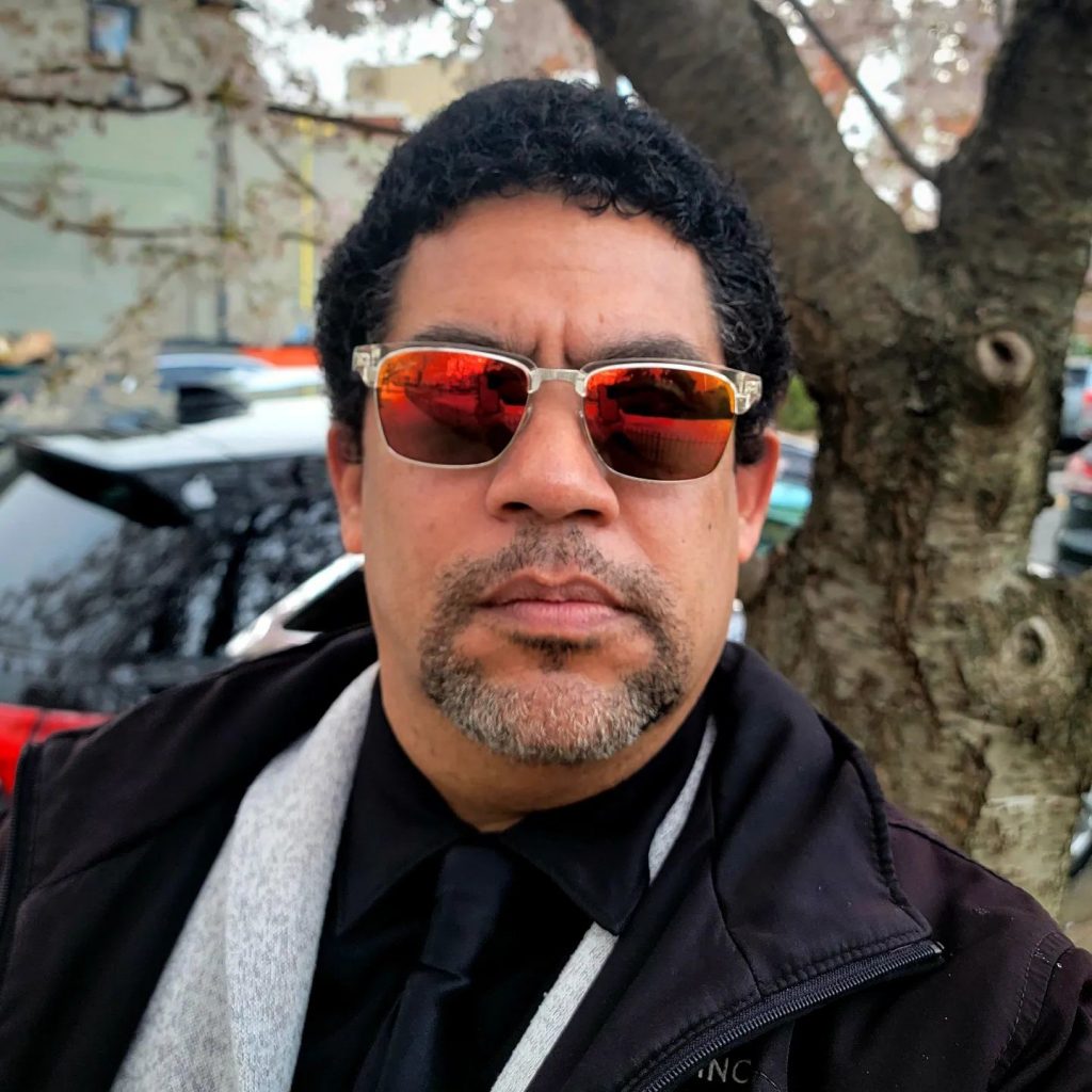 A man in a coat next to a tree