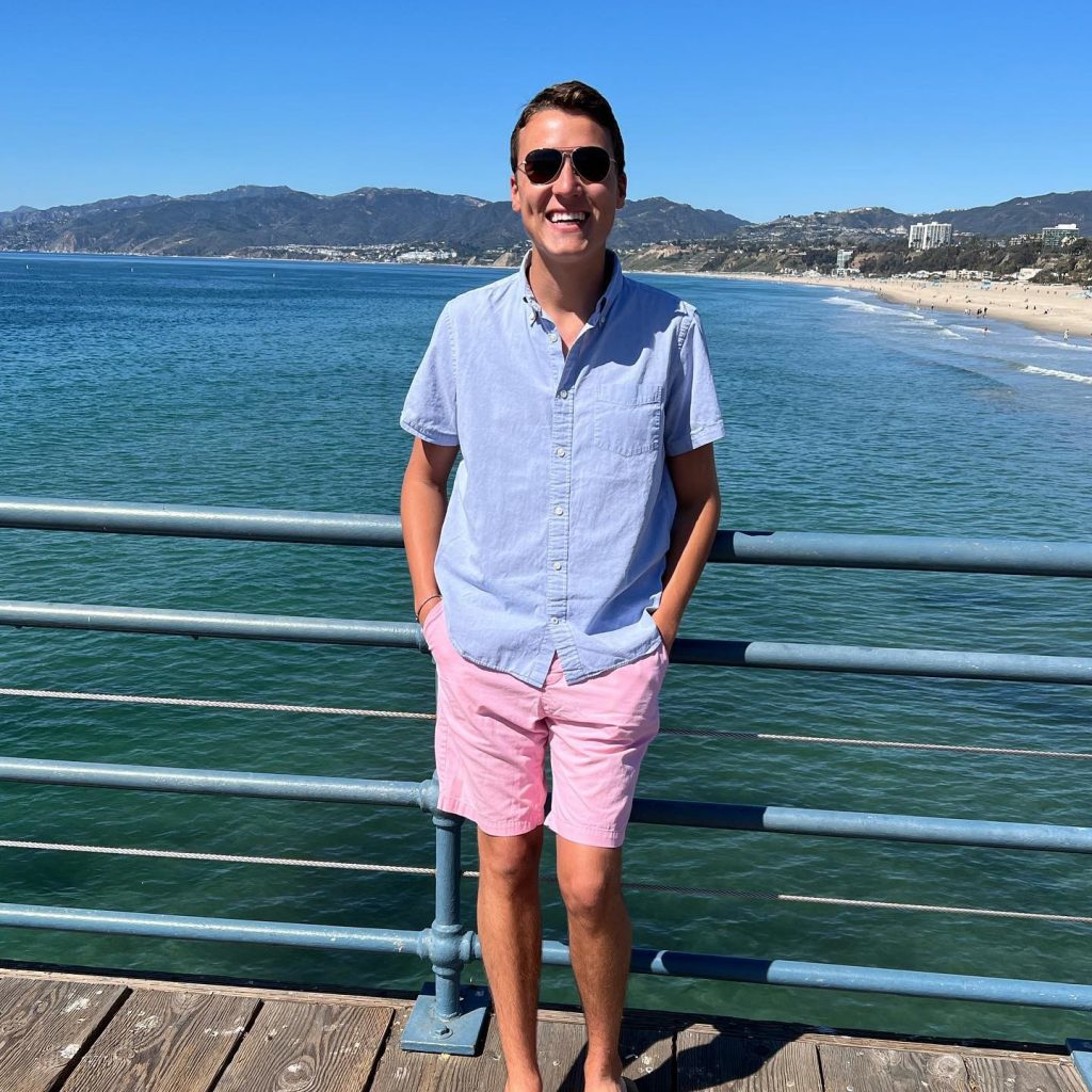 A man leaning on a rail next to open water