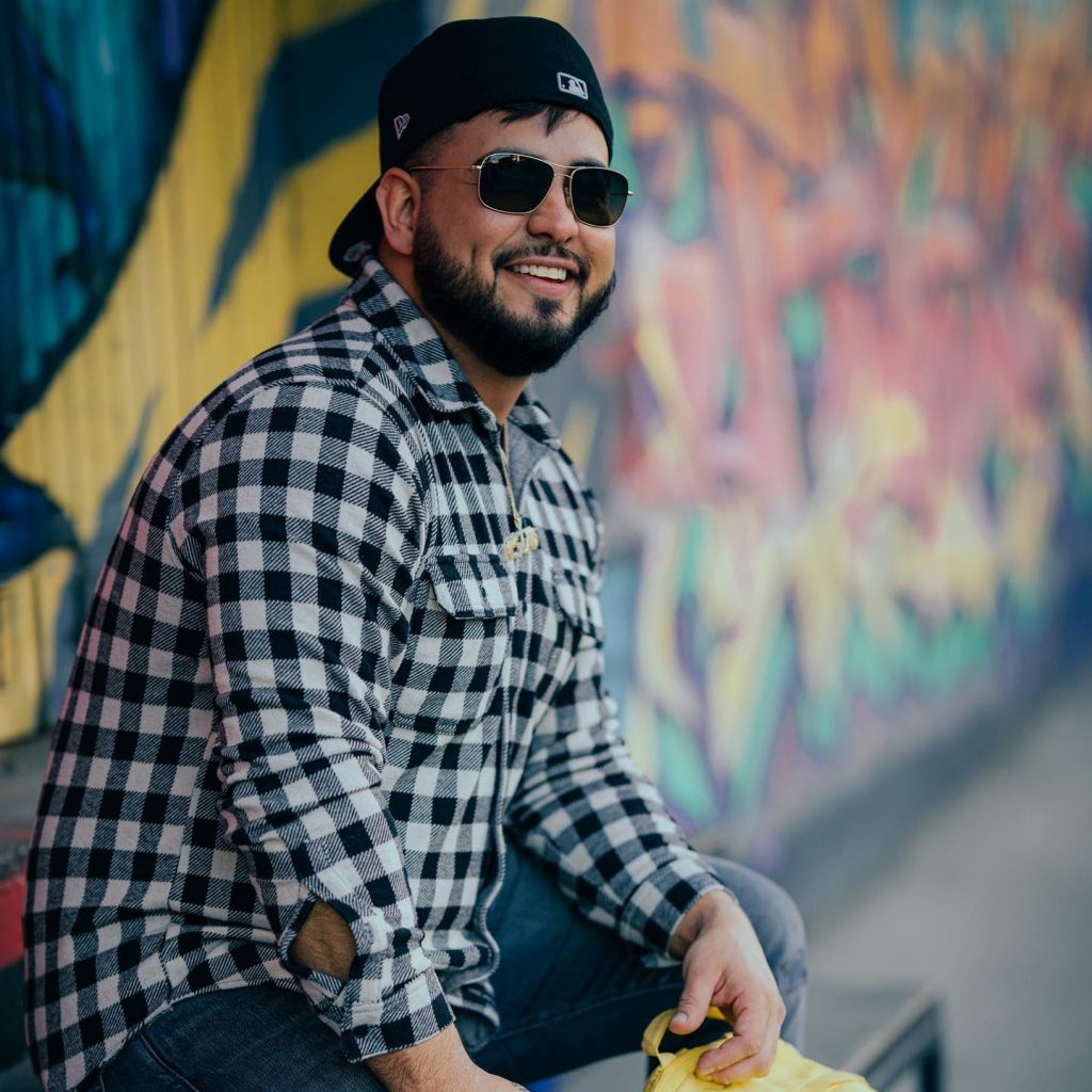 A man in a baseball cap sitting next to graffiti