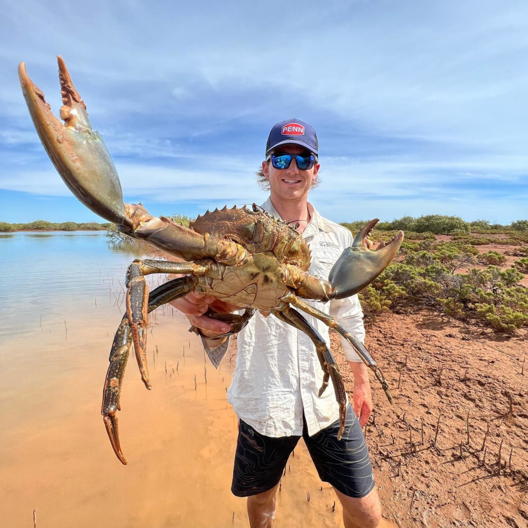 man holding a crab next to lake