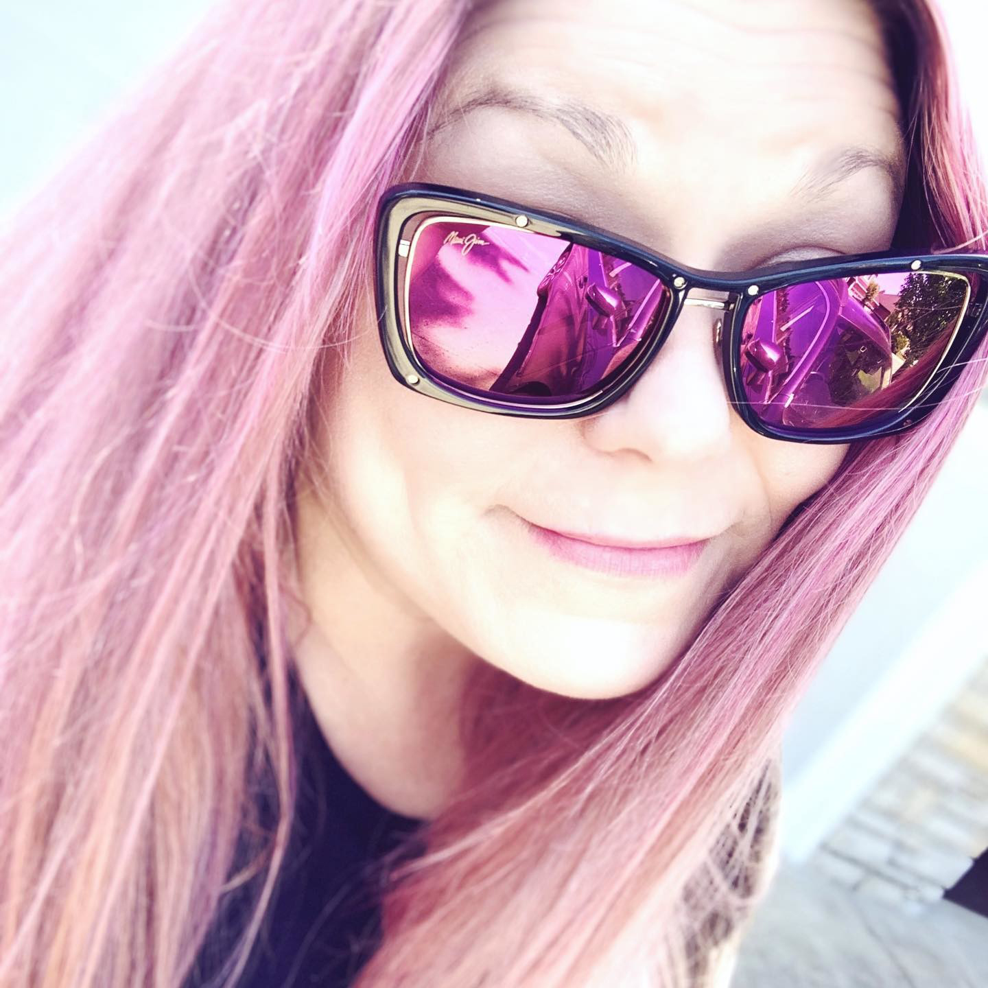Woman with pink hair smiles for a selfie. She is wearing Adrift luxury sunglasses with MAUI Sunrise lenses