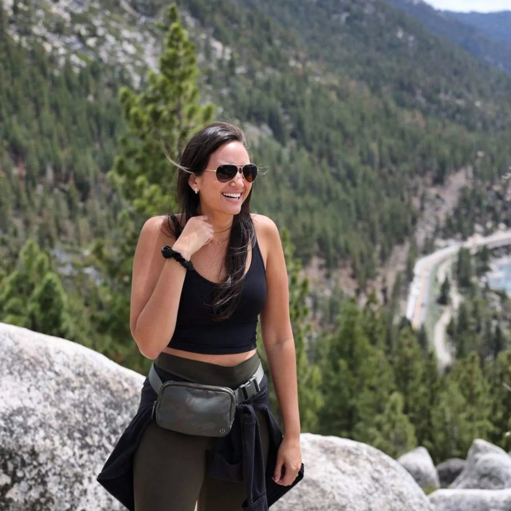 Woman in polarized aviator sunglasses poses on top of a mountain, smiling