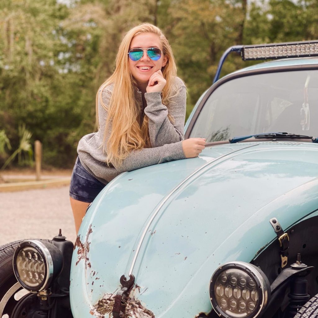 Caroline leaning on an old car